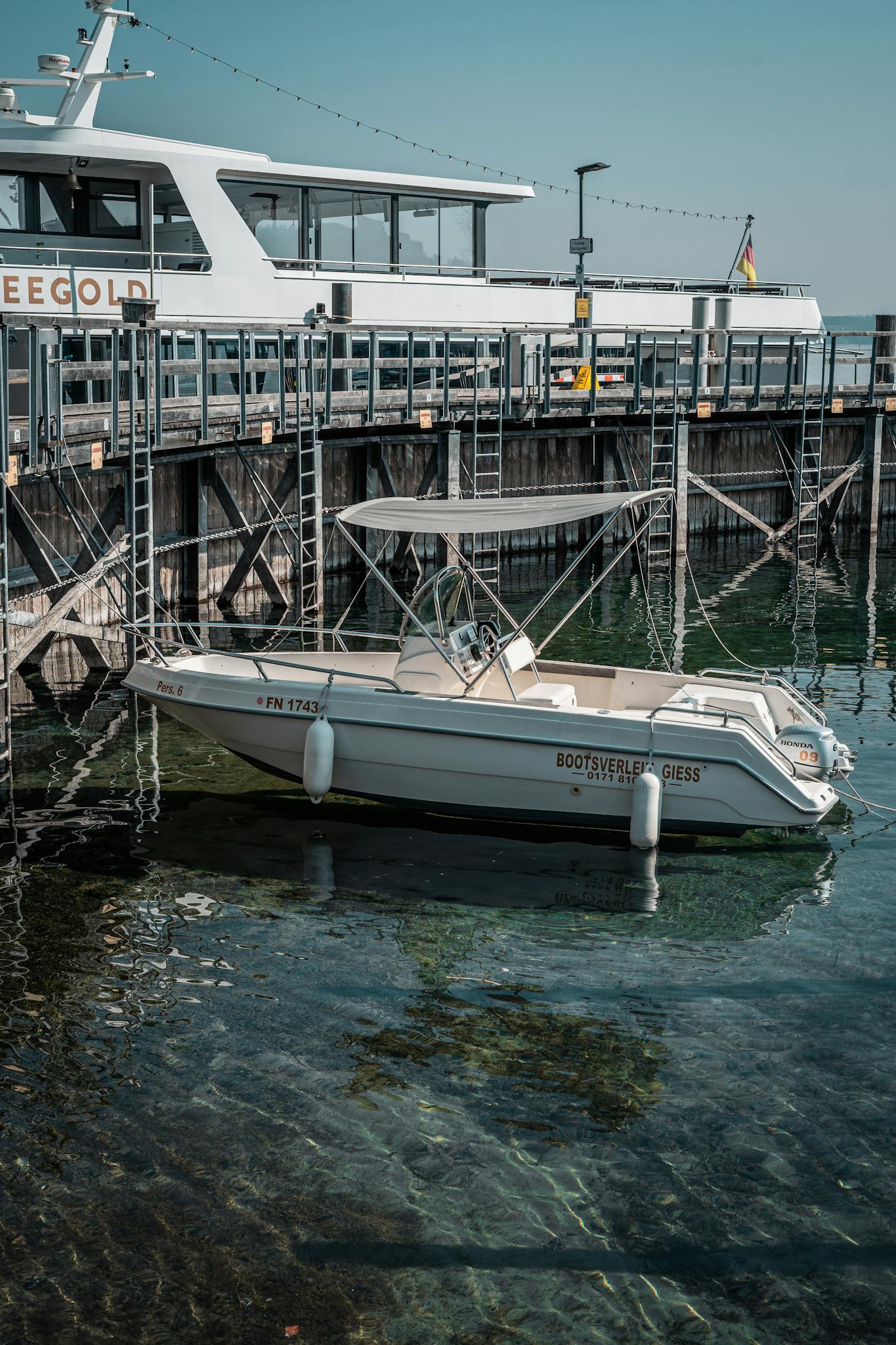 A peaceful marina scene with a docked speedboat and yacht on a sunny day.